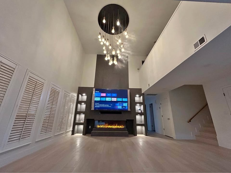 Sala de doble altura con chimenea eléctrica y TV empotrada