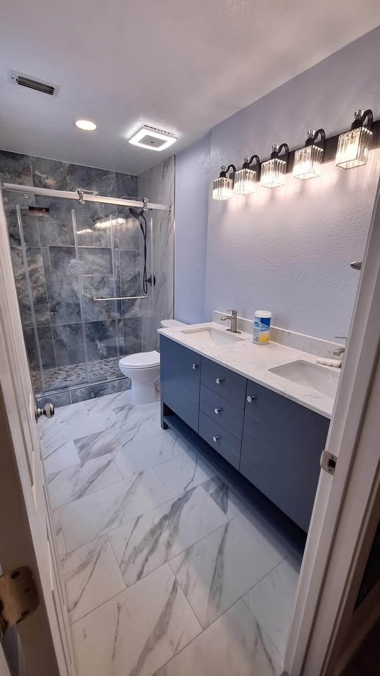 Baño con vanidad doble azul y piso de mármol