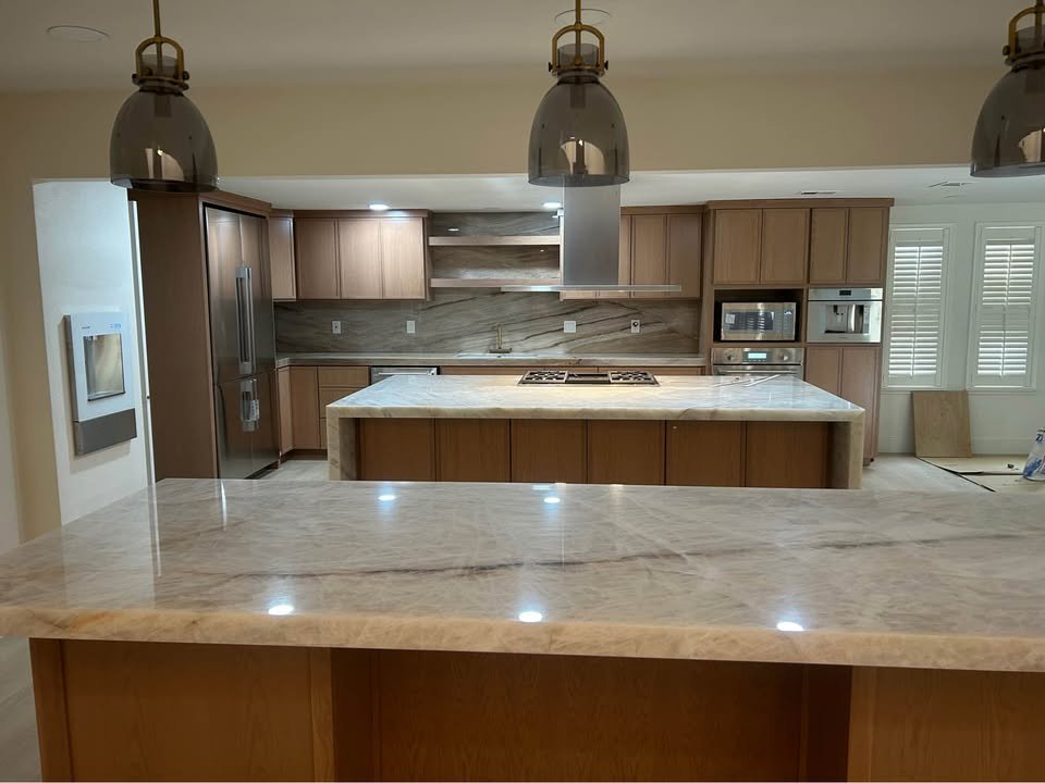Cocina con isla de cuarzo tipo cascada y gabinetes de madera