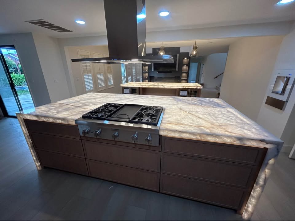Cocina remodelada con isla de mármol y estufa de gas empotrada