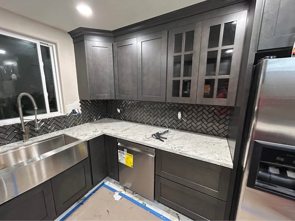 Gabinetes oscuros con encimera de cuarzo y backsplash de mosaico
